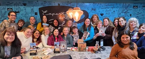 Más de veinte lectores reunidos alrededor de una mesa larga en un café, varios sosteniendo ejemplares de La Restauradora