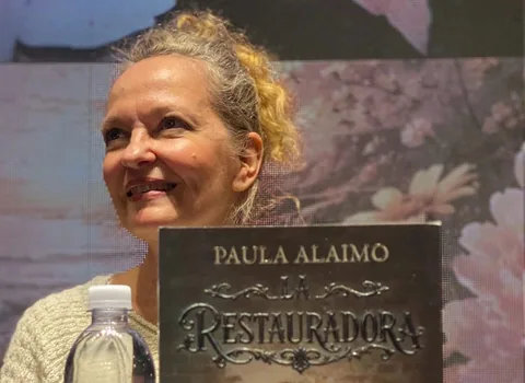 Paula Alaimo durante una presentación literaria, junto a un ejemplar de La Restauradora